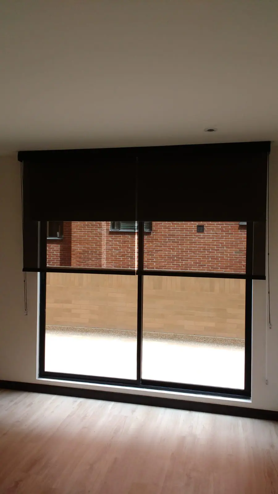 Cortinas enrollables negras instaladas en un ventanal amplio