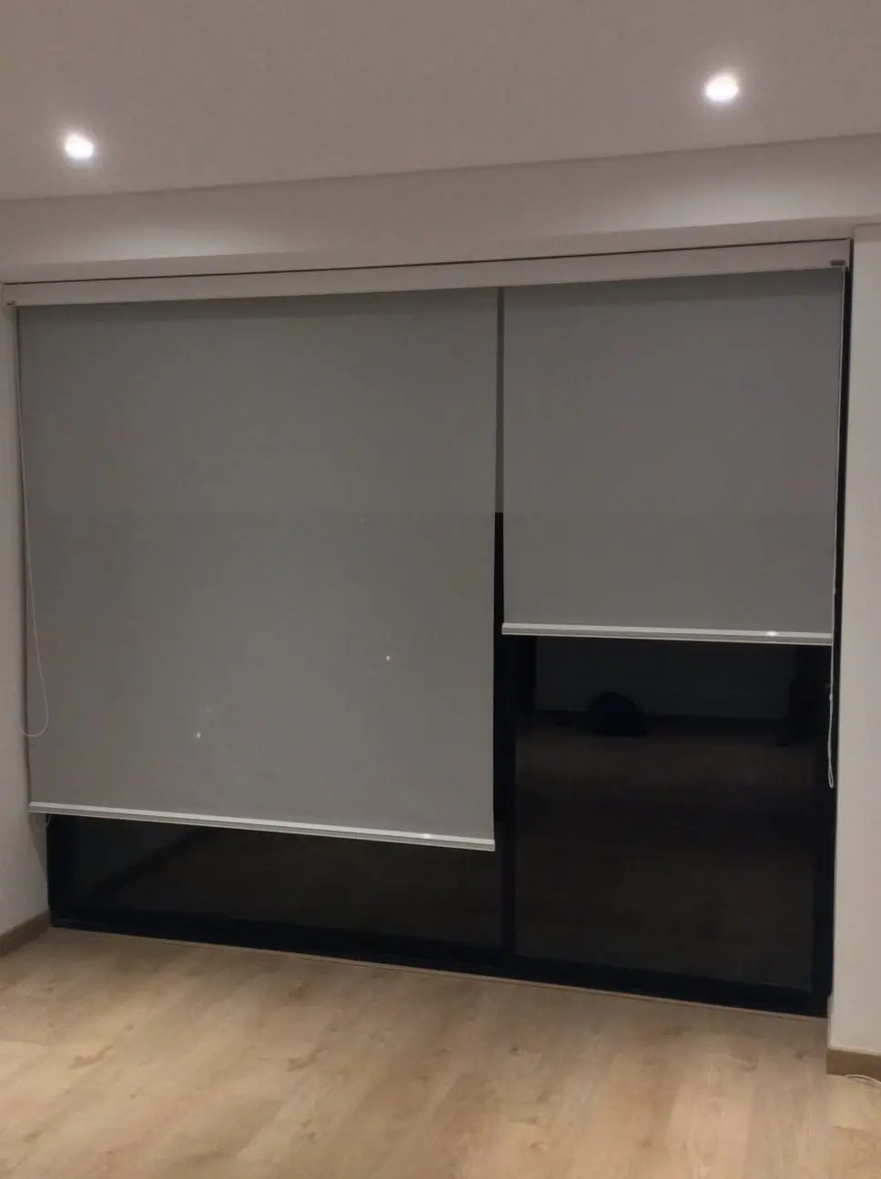 Dos cortinas enrollables grises instaladas sobre un ventanal