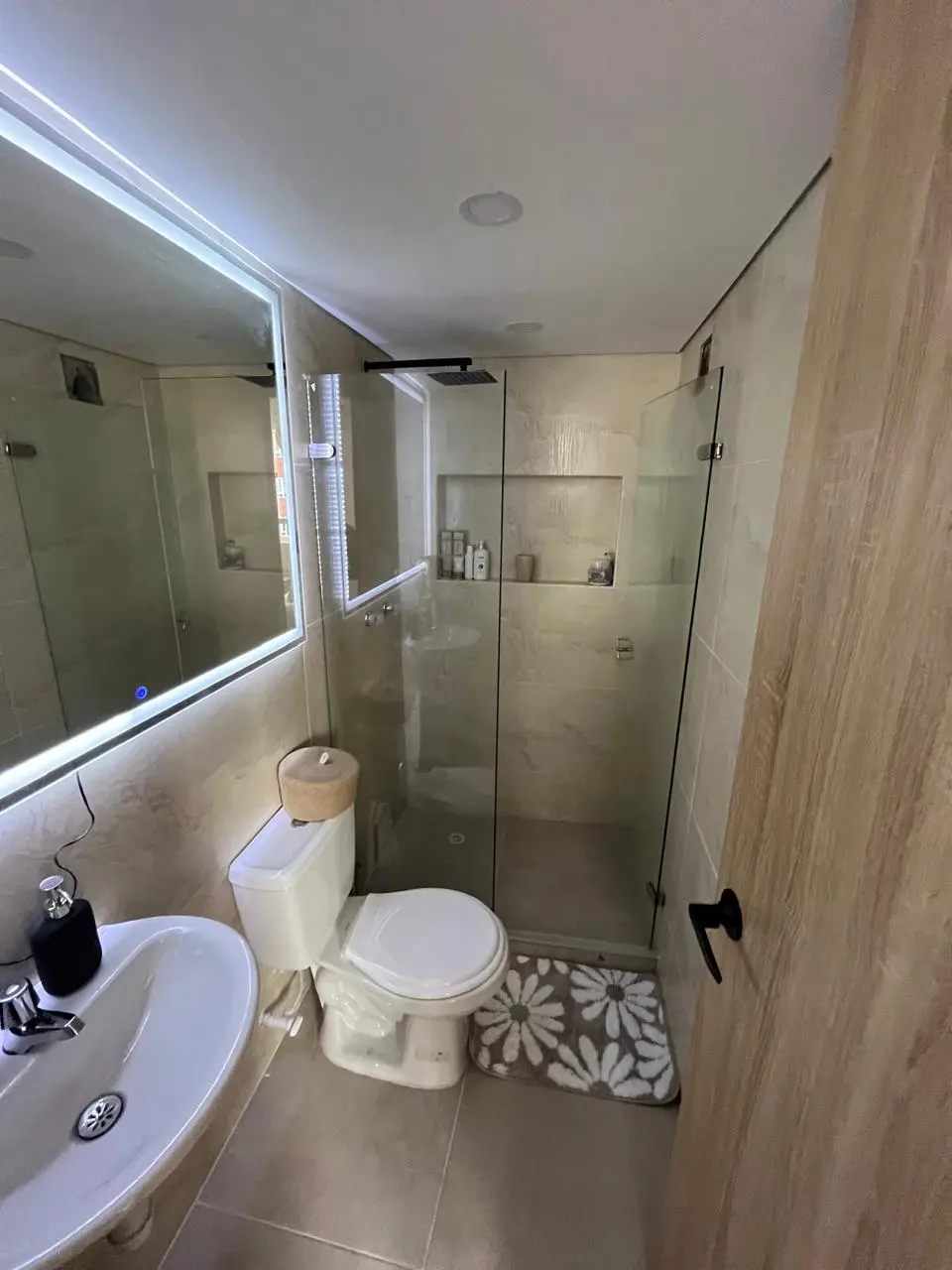 División de baño en vidrio instalada alrededor de la ducha, con puerta y herrajes