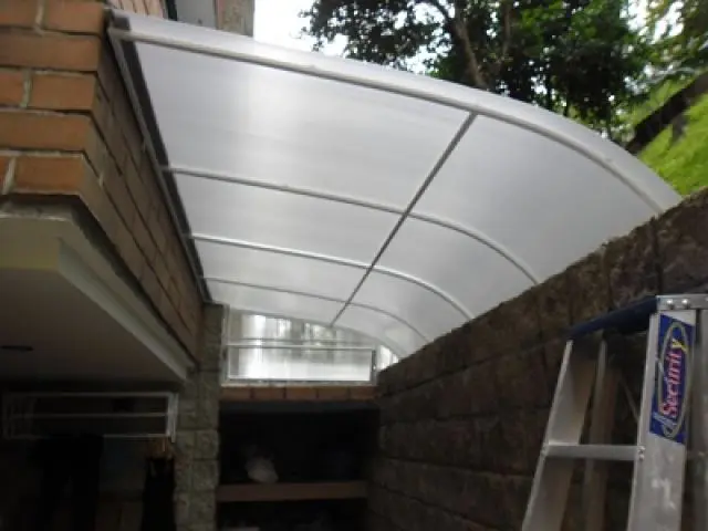 Marquesina curva de policarbonato instalada sobre un pasillo lateral