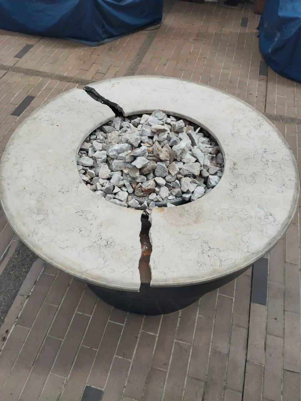 Mesa-fogata circular de exterior con el aro de piedra fracturado antes de la reparación