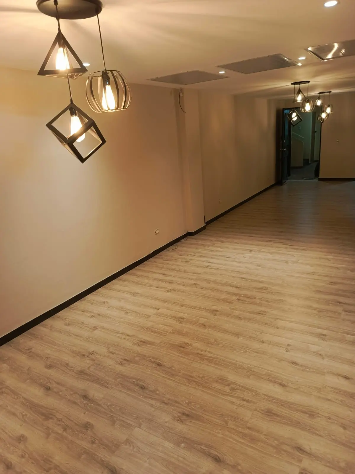 Salón terminado con piso tipo madera y luminarias instaladas