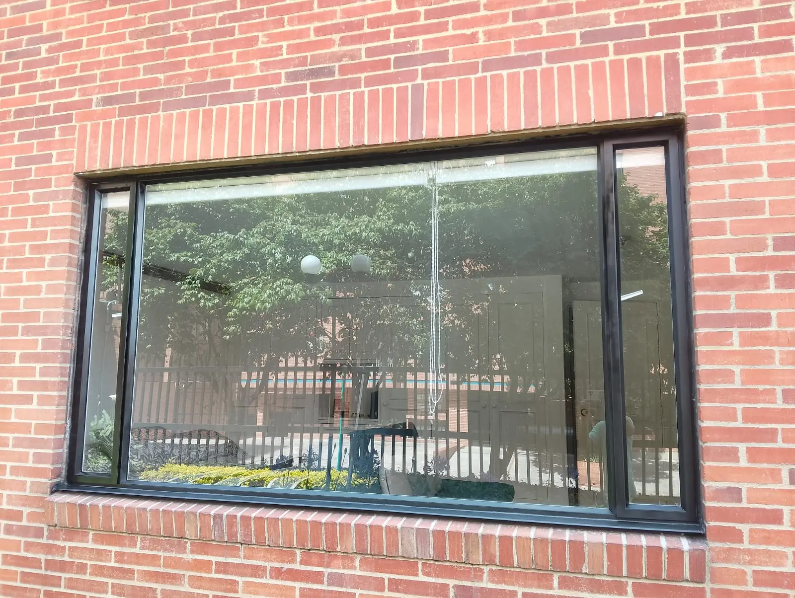 Ventana panorámica renovada con perfilería negra de aluminio y vidrio limpio
